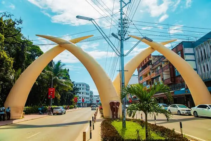 Four white tusks of the Mombasa Tusks monument over a city street