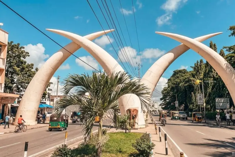 The white Mombasa Tusks crossing above Moi Avenue, with tuk-tuks and a palm